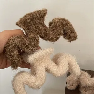 Détail d'une pince à cheveux ondulée en fausse fourrure bouclée beige et marron