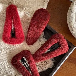 Deep red plush BB hair clips set with fuzzy wool texture on a wooden tray for women