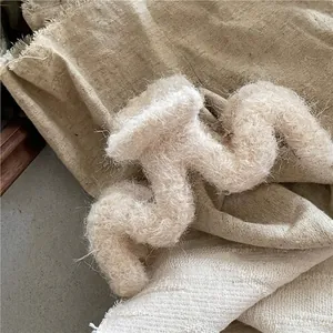 Détail d'une pince à cheveux beige en peluche ondulée avec une texture laineuse douce