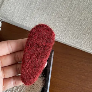 Close-up of a burgundy plush fabric hair clip showing soft knitted texture and detail