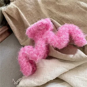 Détail d'une pince à cheveux en peluche rose duveteuse sur fond en lin texturé neutre