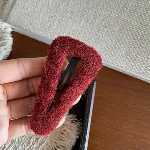 Detailed close-up of a red plush triangular hair clip with soft curly fleece texture