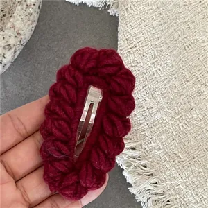 Dettaglio molletta per capelli in maglia rosso scuro con trama all'uncinetto e clip in metallo