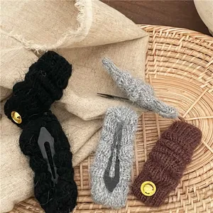 Dettaglio di fermagli per capelli BB in maglia morbida con logo dorato e trama calda