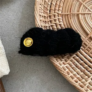 Dettaglio macro del fermaglio per capelli in maglia nera con emblema in metallo dorato