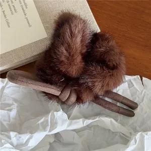 Gros plan d'un chouchou en fausse fourrure marron avec nœud sur un fond texturé chaud