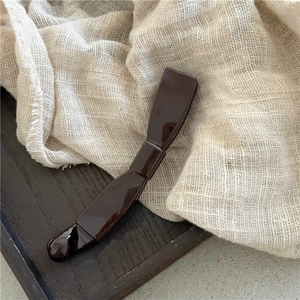 Close-up of a dark brown banana hair clip with a polished finish on a rustic wooden tray