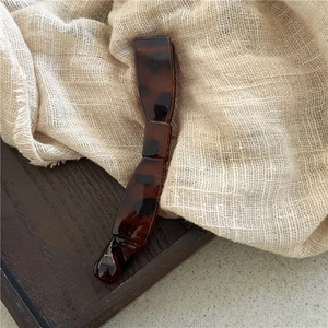 Detailed macro view of glossy dark tortoiseshell banana hair clip on a wooden tray