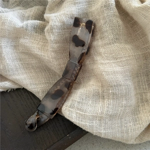 Detailed view of elegant leopard print banana hair clip on a textured fabric background