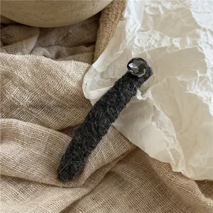 Detail of plush grey velvet hair clip featuring a faceted square rhinestone decoration