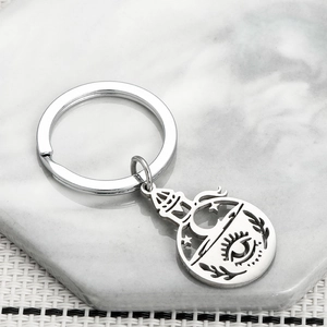 Detail of bohemian magic potion bottle keychain with moon and star cutout on marble tray