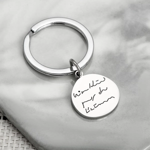 Polished stainless steel round keychain with custom engraving on marble background