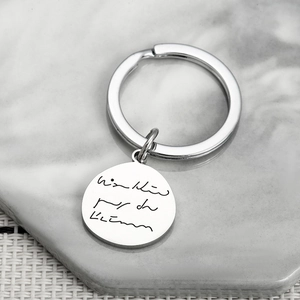 Custom engraved stainless steel keychain with handwritten signature on marble stand