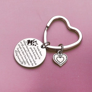 Stainless steel panda keychain with heart-shaped ring and engraved round charm on pink background