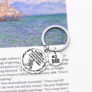 Polished stainless steel Dad hero keychain with sentimental quote on artistic book background