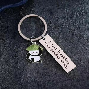 Stainless steel panda keychain with motivational tag on a textured stone surface