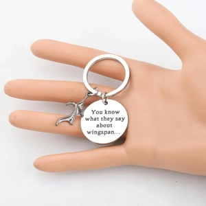 Stainless steel bat wing keychain with engraved quote shown on a mannequin hand