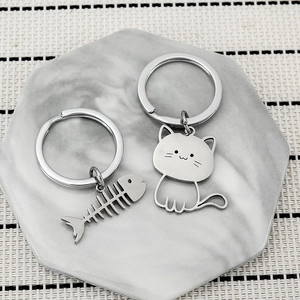 Minimalist stainless steel fishbone and cat keychain set on a marble texture tray