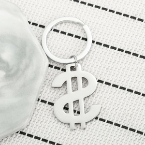 Polished stainless steel dollar sign keychain on a textured background for car keys