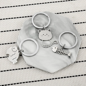 Macro detail of silver cat fish bone keychain set on marble tray with striped background