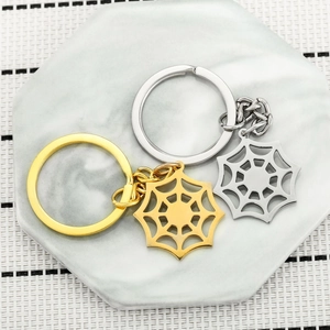Polished gold and silver stainless steel spider web keychains for couples on marble background