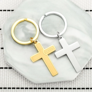 Minimalist stainless steel cross keychains in gold and silver on a marble base