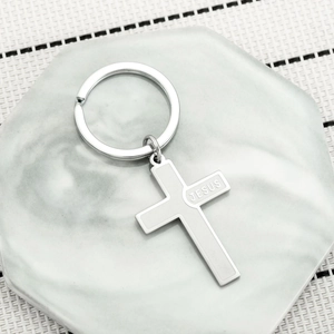 Polished stainless steel cross keychain with JESUS engraving on marble display stand