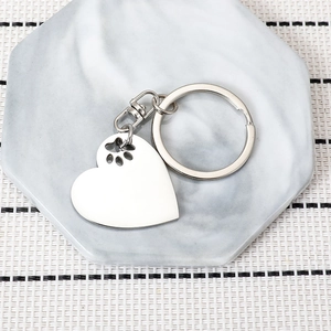 Polished heart keychain with paw print cutout on marble base, silver stainless steel gift
