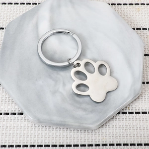 Polished stainless steel cat paw keychain pendant on marble surface for pet lovers gift