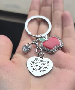 Macro shot of teacher keychain with red enamel apple and engraved heart pendants