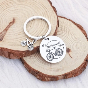 Stainless steel bicycle retirement plan keychain on a wooden base with plush background