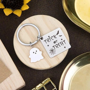 Cute ghost Trick or Treat stainless steel keychain on a stylish wooden tray