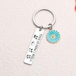 Detail of panda keychain with This Is How I Roll text and blue daisy flower charm