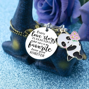 Détail du médaillon en acier gravé et du pendentif panda sur un fond décoratif bleu