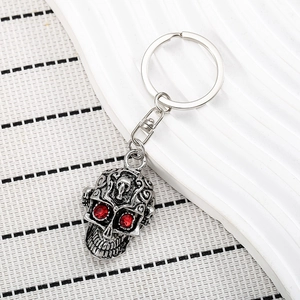 Porte-clés tête de mort punk avec yeux en pierres rouges et motifs en métal embossé
