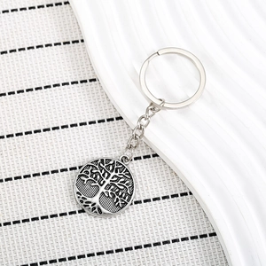 Vintage silver Tree of Life metal keychain with punk style pendant on white ceramic plate