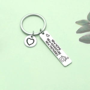 New home keychain with engraved rectangle tag and heart charm on green surface