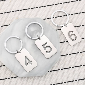Polished stainless steel number keychains 4, 5, and 6 on a marble surface background