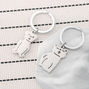 Minimalist stainless steel cat and dog keychains for pet lovers on marble background