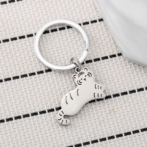 Cute silver tiger keychain pendant with black engraved stripes on a beige woven mat