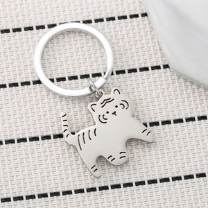 Silver cartoon tiger stainless steel keychain with engraved stripes on a grid fabric