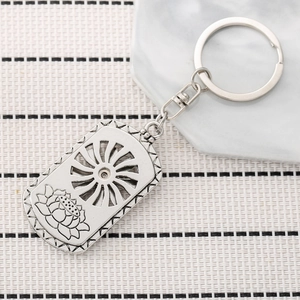 Vintage silver rotating lotus metal keychain with square pendant on marble surface