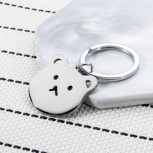 Cute silver stainless steel cartoon bear keychain on a marble tray for backpack decor