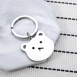 Polished stainless steel bear head keychain for backpack on marble surface