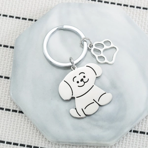 Cartoon dog stainless steel keychain with paw charm on marble background