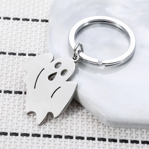 Cute ghost shaped stainless steel keychain with hollow eyes on white marble tray