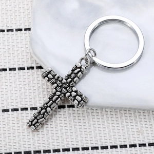 Macro detail of vintage silver cross keychain with pebble texture and metallic keyring