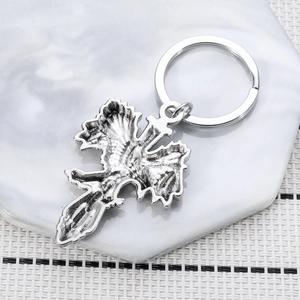 Vintage eagle cross keychain in silver metal on a white marble hexagonal display tray