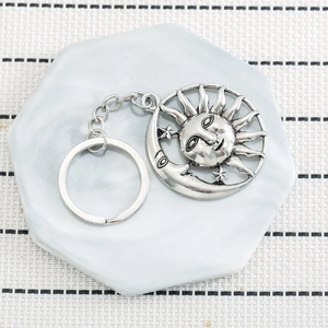 Retro sun and moon keychain in antique silver alloy on a marble tray background