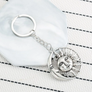 Vintage sun and moon metal keychain with asymmetric bohemian style on marble background